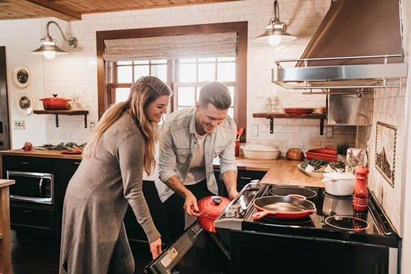 Happy couple opening oven in kitchen